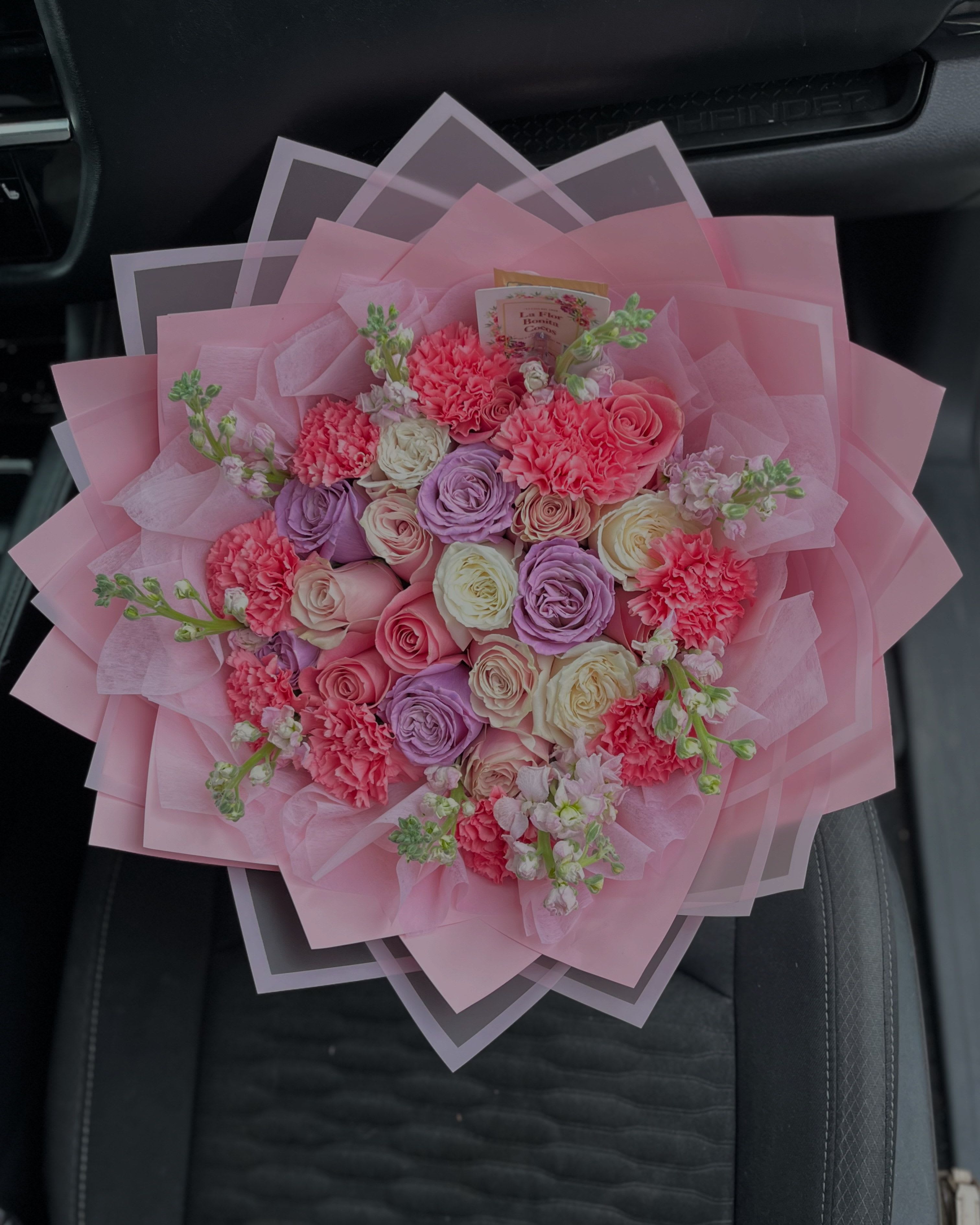 Pink bouquet of roses and carnations wrapped in layered pink paper