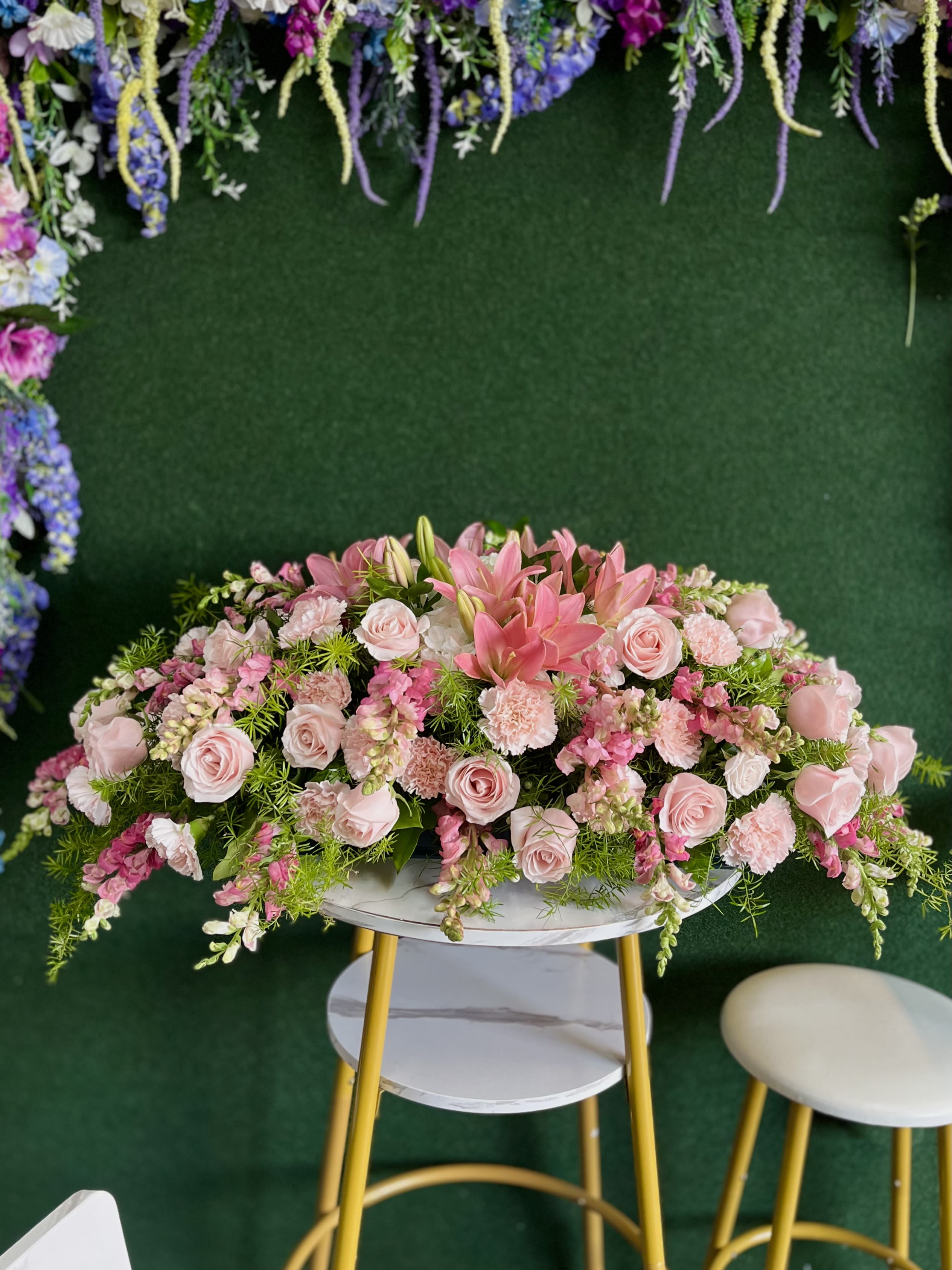 Large pink floral arrangement with roses and lilies on a round table