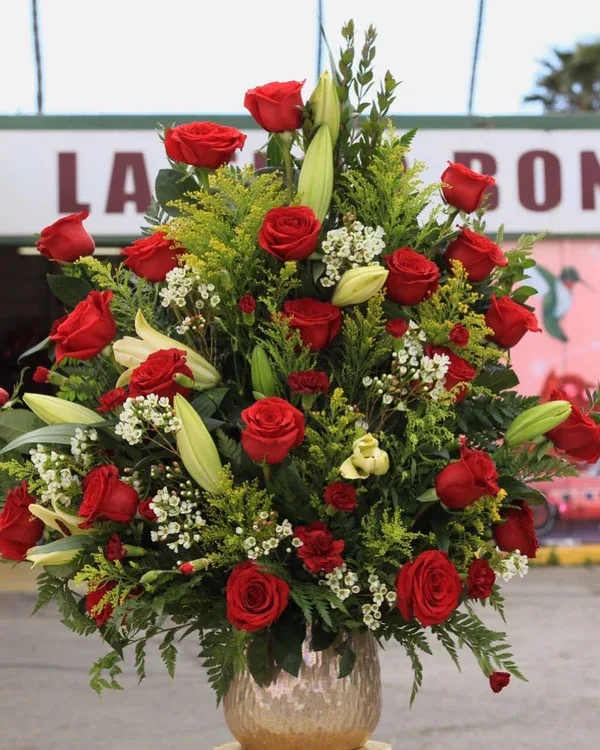Tall arrangement of red roses and lilies in a glass vase