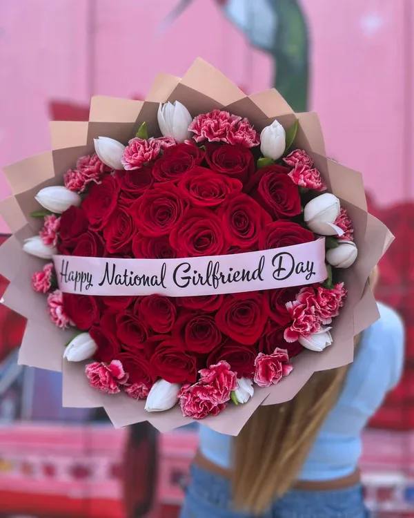 Bouquet of red roses, pink carnations, and white tulips with a ribbon