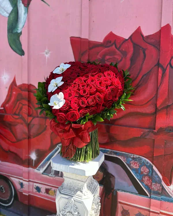 Heart-shaped bouquet of red roses with white flowers and a red ribbon