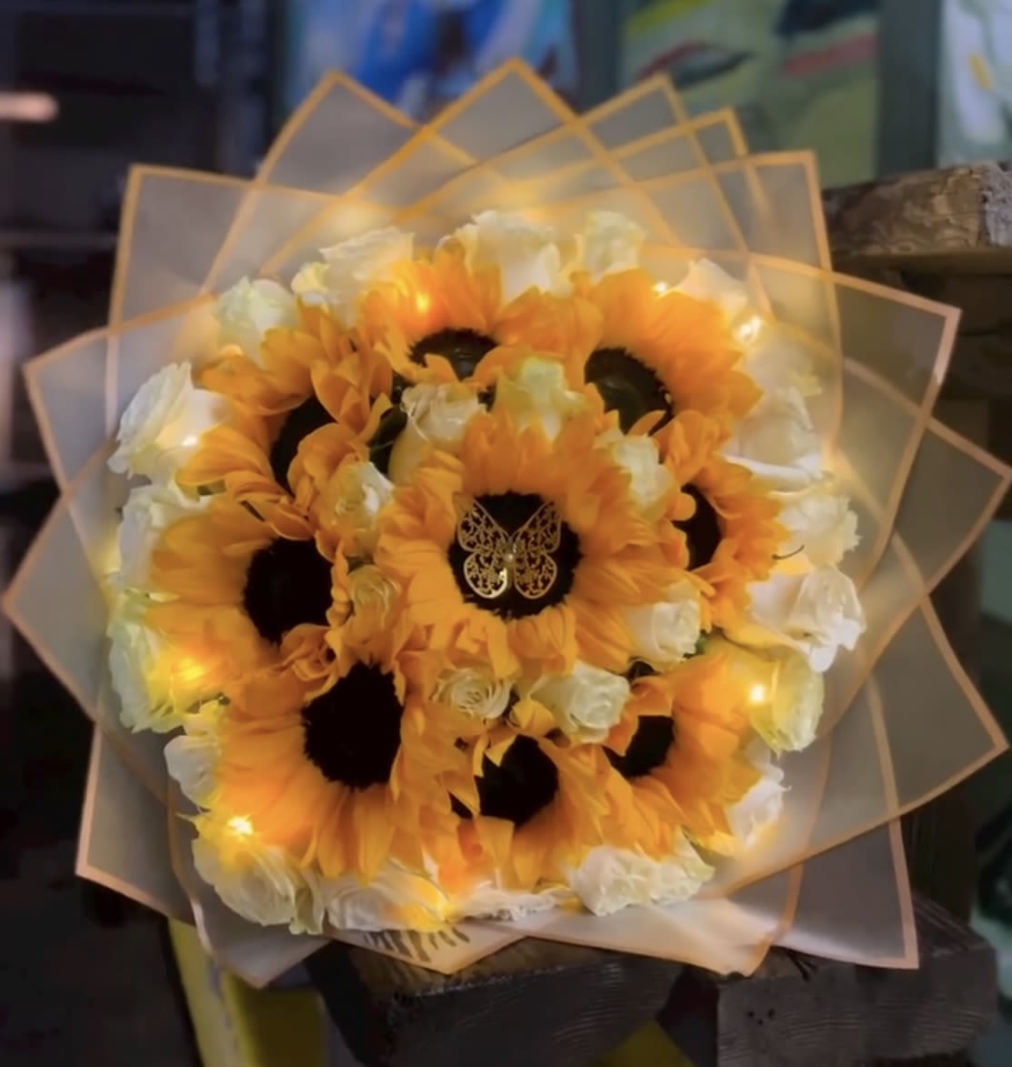 Bouquet of orange sunflowers and white roses wrapped in translucent paper