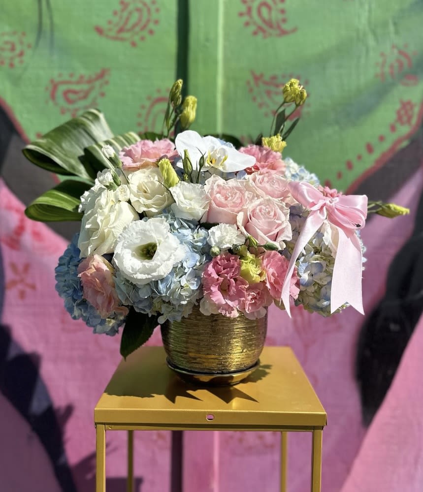 Mixed pastel flower arrangement in a gold pot with a pink ribbon
