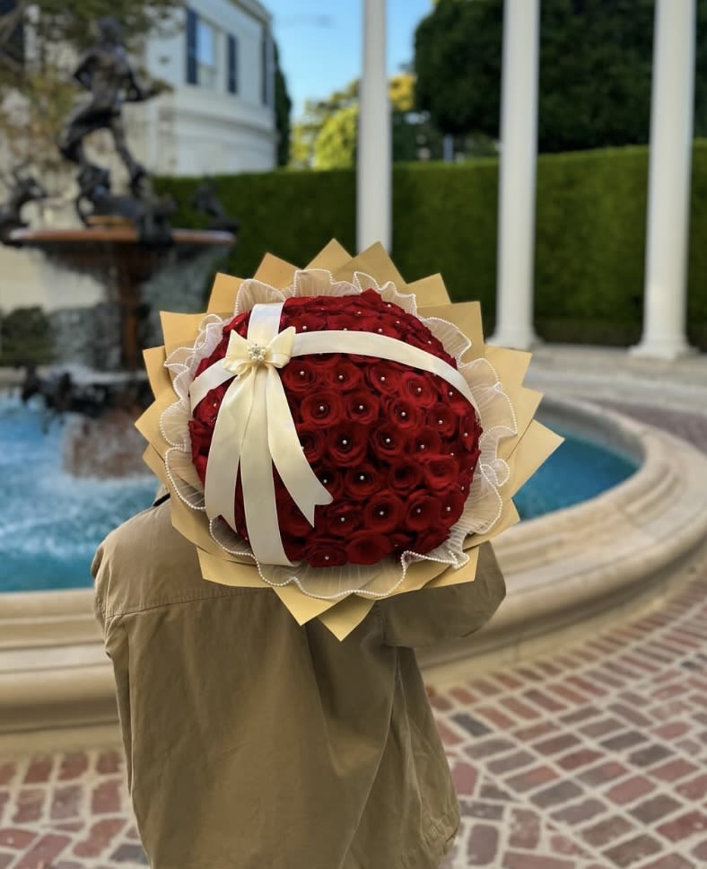 Round bouquet of red roses with a cream ribbon and tan wrap