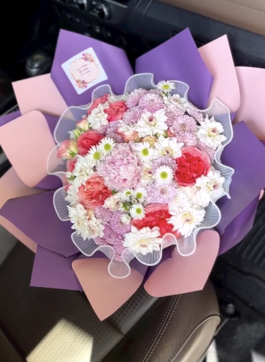 Bouquet of pink, white, and purple flowers wrapped in pastel paper