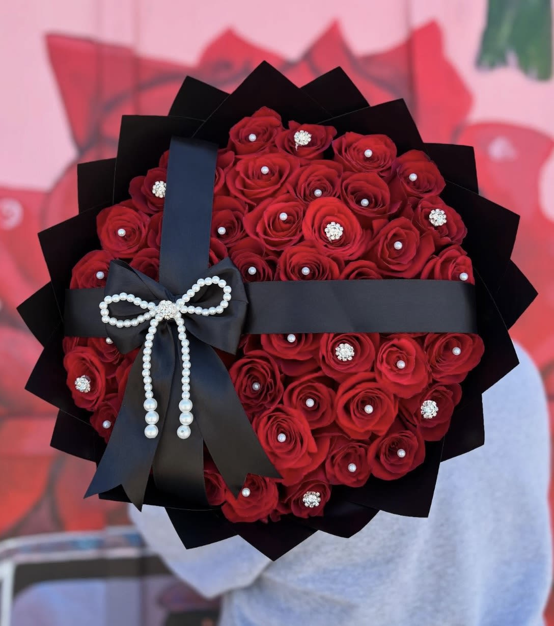 Bouquet of red roses wrapped in black paper with a pearl bow