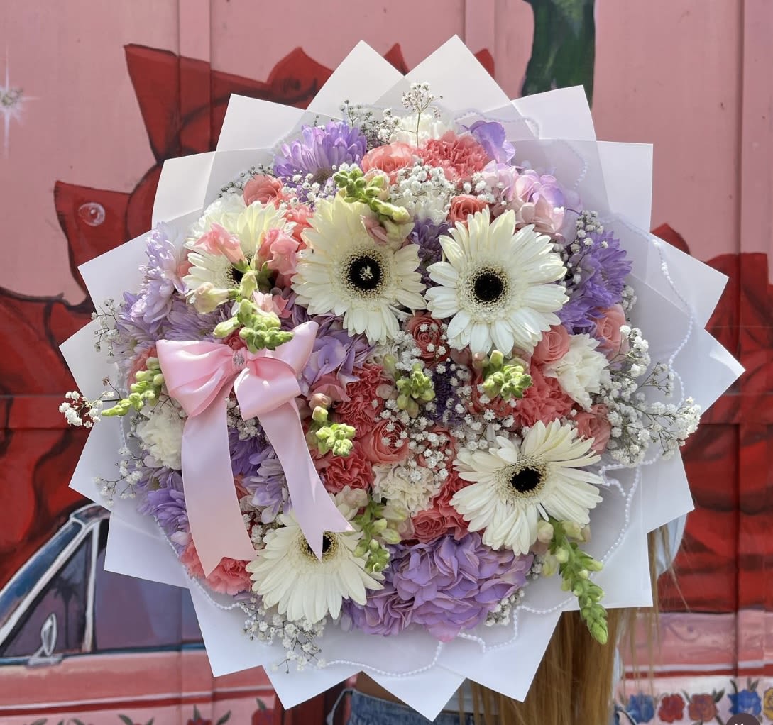 Round bouquet of pastel flowers with a pink ribbon