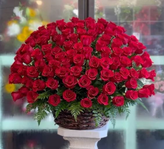 Large bouquet of red roses in a woven basket on a pedestal