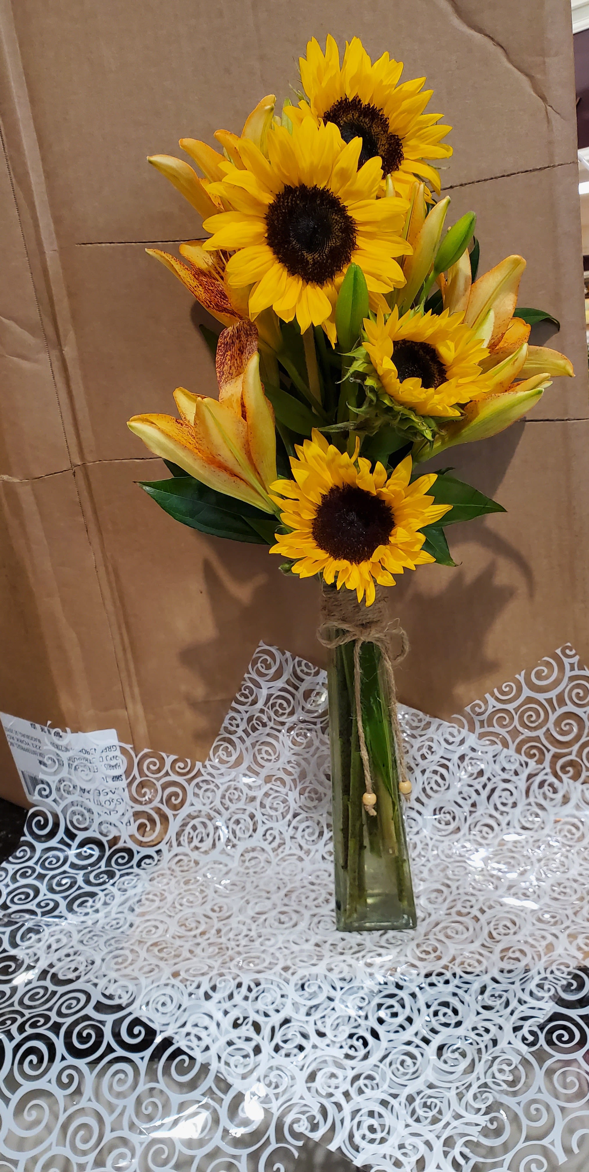 Sunflowers and lilies arranged in a tall glass vase