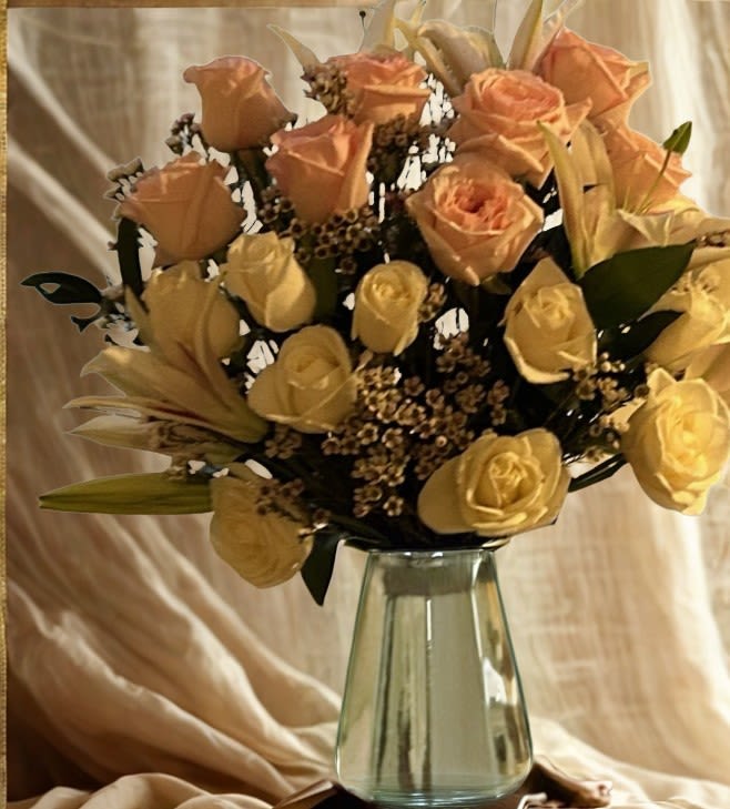 Peach and yellow roses arranged in a clear glass vase