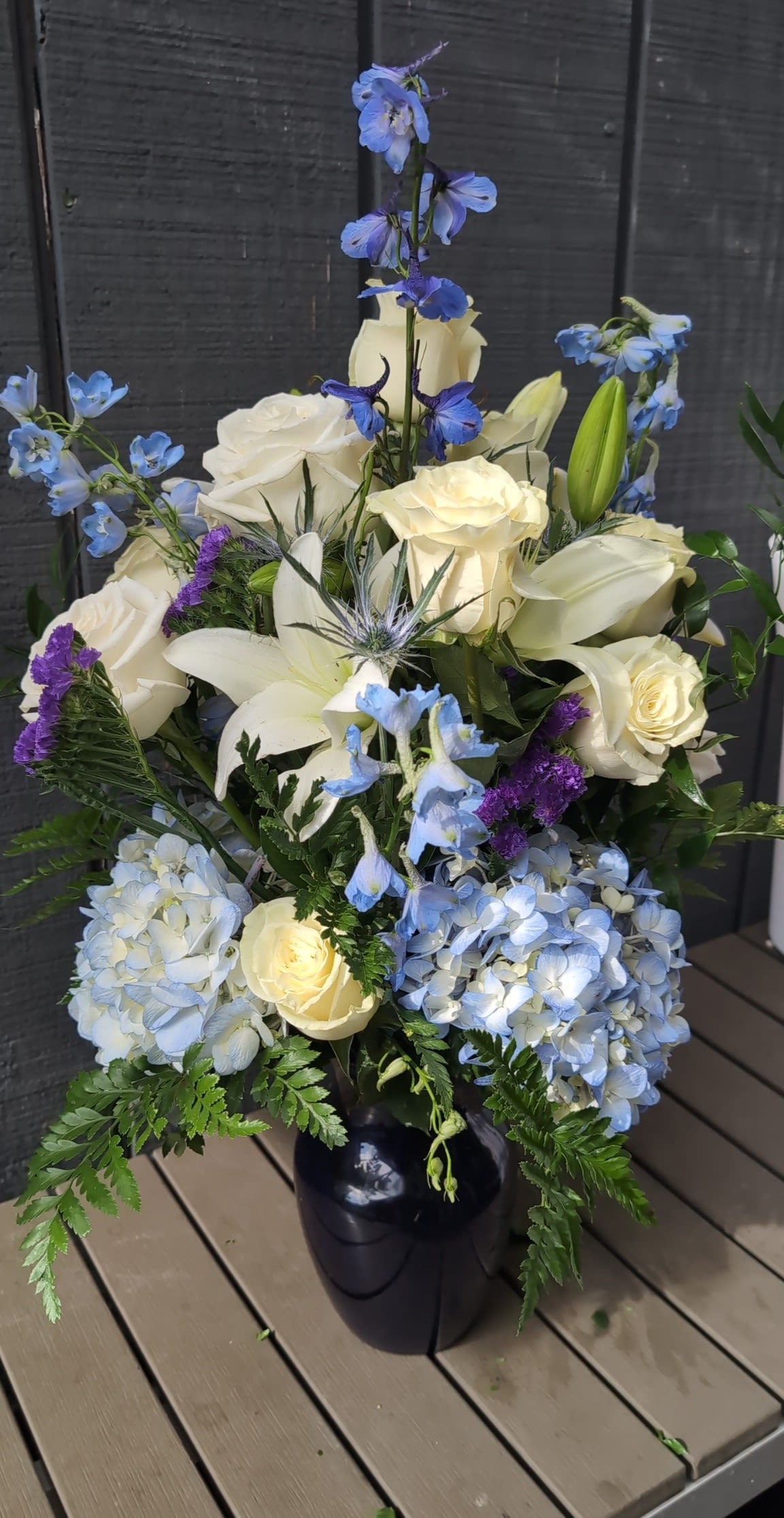 Touch the sky  - Pale blue hydrangeas and sky-blue delphinium spikes rise among creamy white roses and lilies in an arrangement made to lift the spirit - a serene flower arrangement perfect for sympathy, a refined wedding table, or any occasion that calls for quiet elegance. The cool palette of white, blue, purple, and green creates a calm, uplifted impression so the person you're thinking of will feel cared for and seen without overwhelming flash.  deal for sending condolences, celebrating a wedding, or marking any significant moment with quiet dignity, this arrangement arrives ready to display - a statement of sympathy or celebration that feels thoughtful and refined. Care: keep in fresh water, away from direct heat and drafts, and replace water every couple of days to prolong bloom life.