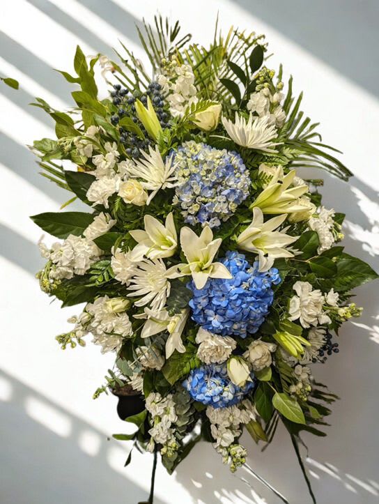 Large floral standing spray with blue hydrangeas, white lilies, and white blooms