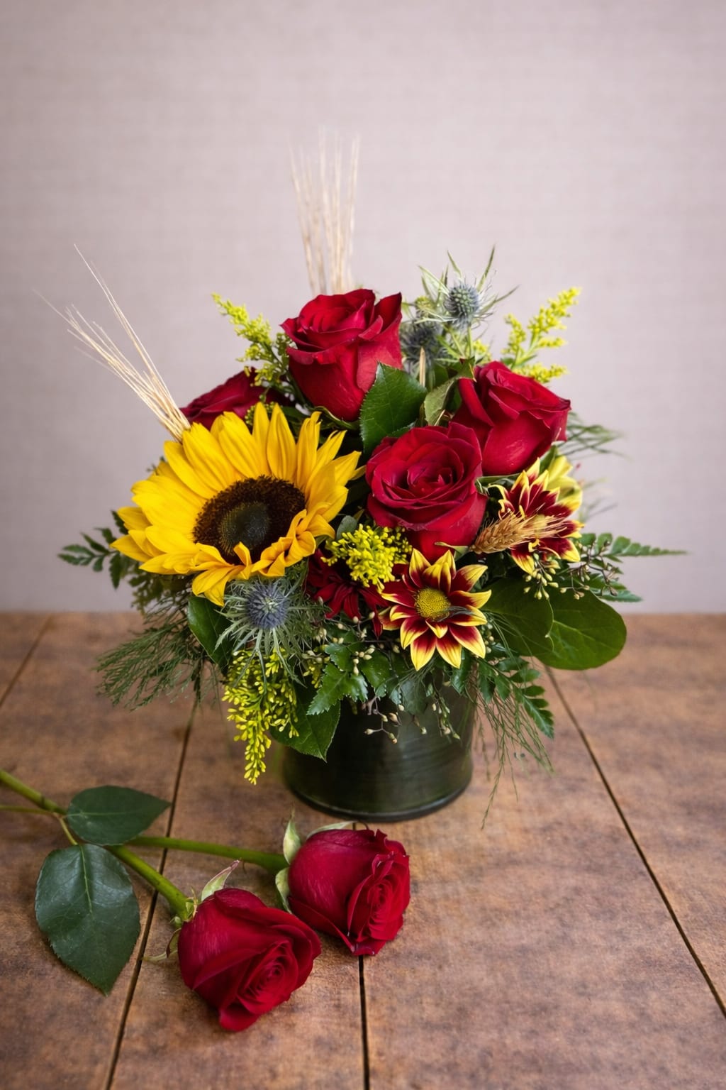 Red roses and a sunflower arranged in a black vase