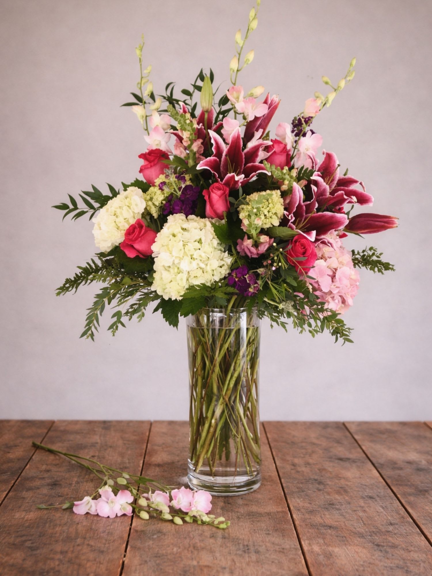 Tall bouquet of pink lilies, roses, and hydrangeas in a glass vase