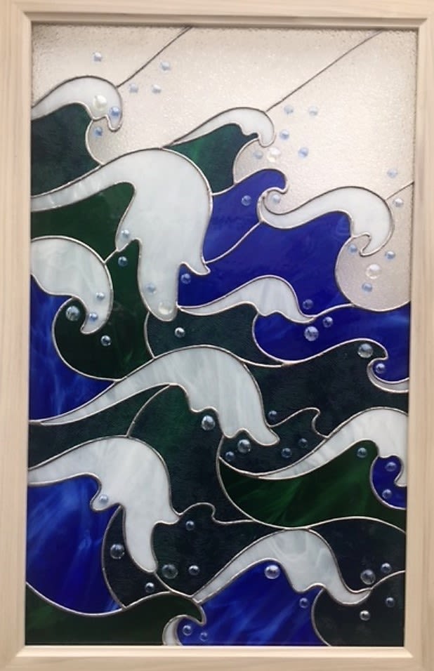 #A073 - Storm At Sea - Layers of deep blue and forest green sweep across a framed stained-glass panel like a calm, rhythmic tide - perfect as a serene wall gift for Mother's Day, an anniversary, or to say "thinking of you." This rectangular stained-glass seascape brings a coastal calm to any room; the white glass crests and foam catch the light, while small rounded accents glint like sea spray, creating a tactile, meditative surface that will soothe the person you're honoring. Hand-set glass in blues, greens and white rests inside a light wood frame that complements both modern and coastal décor. The composition reads like motion-rolling waves and curling crests-so it works beautifully for housewarming, retirement, graduation, or as a thoughtful get-well or sympathy gift when you want to offer quiet comfort. Sized for easy hanging, it's a long-lasting keepsake for birthdays, Father's Day, weddings, or just because, and its seasonal calm suits spring and summer displays while still feeling appropriate year round. This window features a custom poplar frame and is 24" W x 35 3/4" H.