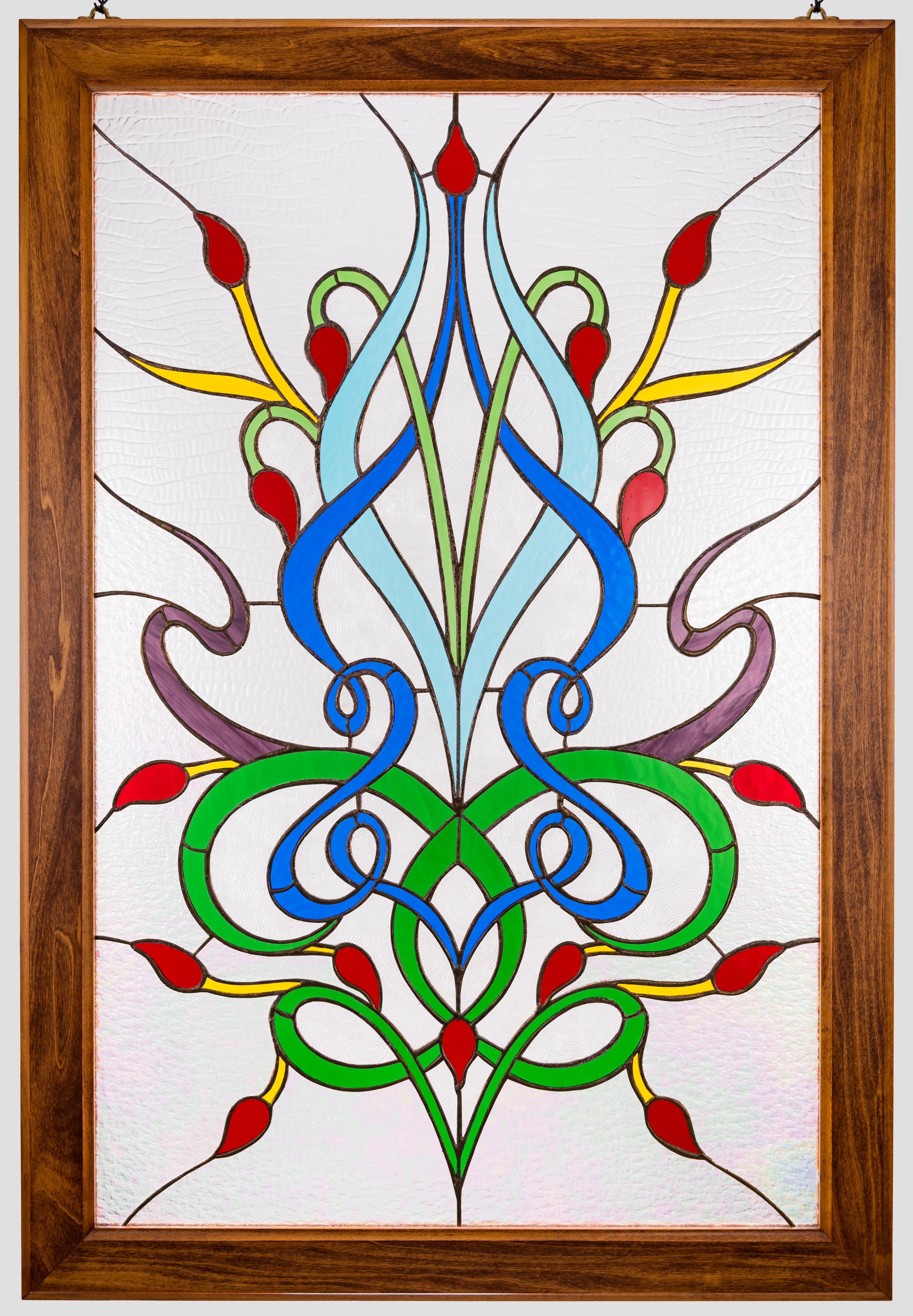 #A125 - Woven Orchid - Stained Glass Window  - A vivid stained-glass floral panel that reads like a miniature window: the woven orchid motif blends vivid blue and green curves with red teardrop "buds" and sunny yellow accents to create an Art Nouveau-inspired flower study - perfect as a flower arrangement alternative for Mother's Day, an anniversary, or a housewarming gift. The piece catches and softens light, so the person you're thinking of will see shifting color and pattern through textured clear glass that feels both decorative and intimate.   Set in a warm wooden frame with included hanging hardware, this arrangement-style panel is finished on both sides with crisp leading and a natural grain border that grounds the bright palette. The design is symmetrical and slightly vintage in mood, about the size of a window insert (wood frame and dimensions available at checkout), and arrives ready to hang in an entryway, kitchen window, or over a mantel.   Give it for birthdays, Father's Day, weddings, graduations, or to say "I'm sorry" or "thank you"-it's the kind of gift that keeps giving light and color season after season from spring through summer and beyond. Care is simple: hang where it receives indirect sunlight, wipe the wooden frame with a dry cloth, and clean the glass with a gentle, non-abrasive cleaner if needed.