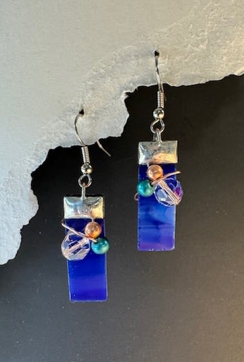 #A075 - Cobalt Blue Stained Glass Earrings - Deep cobalt blue glass drops catch the light with a sleek, modern grace - these dangle earrings make a bold little gift for the person you want to delight. As a gift for an anniversary, birthday, Mother's Day, or "just because" surprise, the vertical rectangular shape reads polished and contemporary while the clustered beads add a warm, handmade touch that feels personal and thoughtful. Each earring features a smooth opaque cobalt rectangle topped in silver-toned metal, accented near center with a small cluster of teal, peach, and clear faceted beads wrapped in fine wire.   The contrast of the glossy blue planes and sparkling beads creates pleasing depth and movement; metal hooks make them easy to wear and the lightweight construction keeps them comfortable through spring and summer celebrations or a night out. Perfect for saying "thinking of you," "thank you," or "I'm sorry" without words, these earrings suit recipients who favor artistic, wearable statements-friends, partners, moms, or the bride seeking a pop of color. They arrive ready to gift and pair beautifully with denim, linen, or a simple black dress for versatile, everyday elegance.