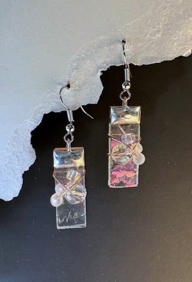 #A067 - Clear Iridized Stained Glass Earrings - Iridescent rectangular resin pendants catch the light with soft swirls of pink, white, and shifting hues - these dangle earrings make a quietly artful gift for Mother's Day, a birthday, or an anniversary. The modern, stained-glass look reads romantic and refined; the person you're celebrating will notice how the colors change with every turn, a small, luminous reminder that you were thinking of them.   Handmade details include silver-toned metal fishhook ear wires, fine wire wrap around each pendant, and a central cluster of tiny translucent and pearly beads for delicate shimmer and texture. The narrow rectangular shape keeps the silhouette sleek and wearable for spring and summer days or layered with cozy winter styles, while the mixed-color finish works equally well for prom, graduation, or a thoughtful "just because" gift.   Perfect for someone who appreciates handmade, artistic jewelry-this piece sends an intimate message for occasions from Valentine's Day and Christmas to retirement, "I'm sorry," or simply "thank you." Lightweight and everyday-friendly, these earrings arrive ready to wear and pair beautifully with both casual denim and dressier outfits for weddings or holiday parties.  Shipping available - select Delivery, then message us to ship.
