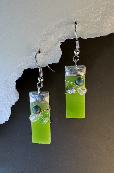 #A071 - Kiwi Green Stained Glass Earrings - A pair of lime-green rectangular glass dangle earrings that catch the light with modern simplicity - perfect as a small gift to tuck alongside a bouquet for Mother's Day, a birthday, or "just because." These contemporary stained-glass earrings read fresh and playful, making them a great accompaniment for spring and summer occasions or a bright surprise for Christmas, Graduation, or an anniversary. The design also suits quieter moments - Get Well, Thinking of You, or I'm Sorry-when you want the person you're thinking of to feel genuinely seen. Each earring features a glossy green glass-like bar topped with a silver-tone cap and hung from a simple metal hook for a lightweight, comfortable wear. They are accented with wired faceted and round crystal beads in iridescent clear, dark, and green tones that add subtle sparkle and texture while the mate keeps a cleaner, minimal silhouette-an intentionally asymmetrical touch that feels artistic and modern. These dangle earrings layer easily with everyday outfits and make a thoughtful add-on for weddings, prom, retirement parties, Valentine's Day, or as a thank-you gift.  Shipping available - select Delivery, then message us to ship.