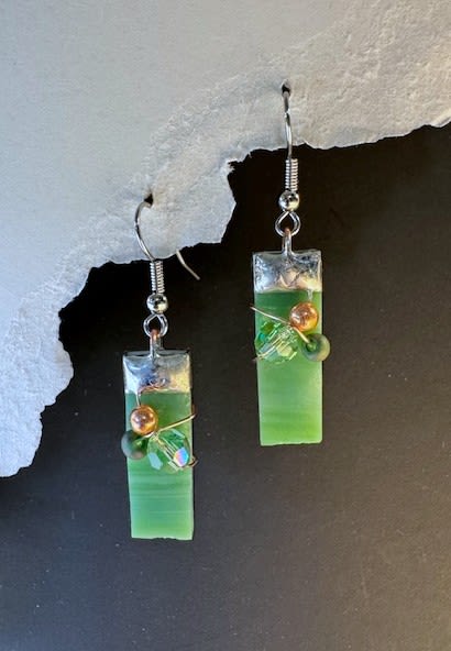 #A006 - Leaf Green Stained Glass Earrings - Vibrant rectangular green glass drops catch the light in these handmade dangle earrings-an artful little keepsake that feels like a mini stained-glass window. As a gift to mark Mother's Day, a birthday, an anniversary, or "just because," these earrings add a thoughtful, wearable accent that will make the person you're thinking of feel seen and celebrated.  Each earring features a slim green glass rectangle capped in silver-toned metal, hung from metal hooks and finished with small round and faceted beads in greens and warm metallics. The wire-wrapped bead clusters add texture and sparkle, giving a modern, layered look that reads fresh for spring and summer yet warms up nicely for autumn and winter gifting.  Perfect tucked into a bouquet or included as a keepsake with a sympathy, get-well, graduation, or retirement arrangement, these lightweight earrings are easy to wear every day. They come ready to gift alongside flowers for weddings, Valentine's Day, Mother's Day, Thanksgiving or Christmas, or kept as a sweet token for thank-you, thinking-of-you, or I'm-sorry moments.  Shipping available - select Delivery, then message us to ship.