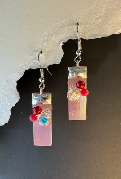 #A058 - Pink Iridized Stained Glass Earrings - Delicate pink iridized rectangular pendants catch the light in these stained-glass dangle earrings, offering a soft, translucent glow that feels both modern and feminine - perfect as a birthday or Mother's Day gift. These fashionable earrings read like a little wearable bouquet: the pastel-pink panels are offset by glossy red round beads and clear faceted accents that sparkle with movement, making them an elegant choice for anniversaries, Valentine's Day, or "just because" surprises. Each earring hangs from a silver-toned cap and metal hook, with fine wire wrapping that secures the decorative beads and adds an artisanal, handcrafted touch. Lightweight and wearable for everyday moments or special nights out - think prom, wedding guest, or a romantic date - they're also a thoughtful pick for get well, thinking of you, or thank-you gestures. Order as a pair for immediate gifting; gentle care (avoid moisture and rough handling) will keep the iridized finish and faceted shine looking fresh season after season.  Shipping available - select Delivery, then message us to ship.