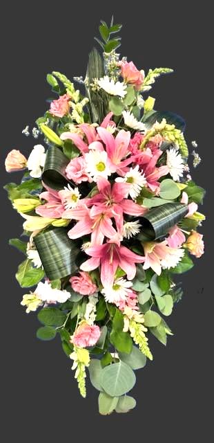 #A031 - Soft Pink Remembrances - Soft pink lilies open like quiet statements at the center of this tall sympathy spray, a flower arrangement designed to convey gentle remembrance and calm. The vertical, tapered silhouette and soft pastel palette make it a fitting funeral tribute or a respectful way to comfort someone after a loss, while also suitable for any moment when you want to offer a composed, thoughtful expression.  Clusters of pale pink carnations nestle between the lilies, while white daisy-like blooms and pale white snapdragon spikes add delicate texture and contrast. Glossy green leaves are artfully looped to create structure and depth, giving the piece a refined, elongated profile that reads formal without feeling severe. Sized as an upright spray, it arrives ready to place at a service or to display at home; its muted tones and layered shapes ensure the recipient feels seen and gently supported.