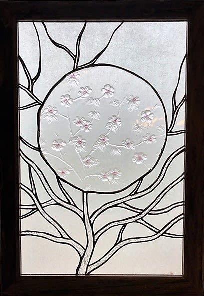 #A055 - A Glimpse of Spring - A sculptural frosted glass panel framed in rich light poplar wood makes a quietly elegant gift for Mother's Day, an anniversary, or a “thinking-of-you” moment. This decorative one-of-a-kind art piece with a floral motif - features linear branches that reach into a large central circle where an antique decorative glass plate displays delicate raised glass blossoms with soft pink centers.  The visual calm of a modern still life is evident here and reads as both floral arrangement and wall-worthy accent. The piece pairs white and clear contrasts with touches of pink to create a serene palette that suits spring, winter, or year-round décor. The frosted glass panel and wood frame combine smooth, tactile surfaces with graphic, nature-inspired lines; it's designed to hang in a window or on the wall, as a focal accent in an entryway, living room, or office. The subtle blossom etching catches light differently through the day, giving the piece quiet. Gift this to the person who appreciates refined simplicity-the new parent who's decorating a nursery, the graduate furnishing a first apartment, or someone you want to comfort after a hard week. It's a thoughtful choice for birthdays, Father's Day, weddings, thank-you gestures, or "just because" moments.