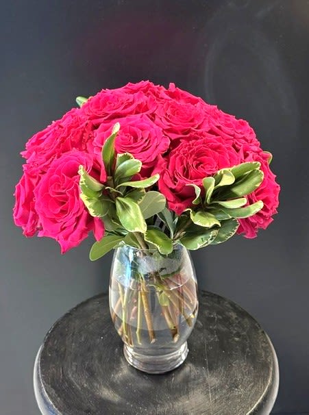 #A090 - Pink Lady - A bold dome of hot pink roses makes an immediate impression - perfect as a birthday bouquet, anniversary roses, or a Mother's Day gift that reads as both romantic and cheerfully celebratory. This compact flower arrangement places those vivid pink blooms in tight, garden-fresh clusters so the person you're thinking of is met with an energetic, heartfelt splash of color the moment it arrives.   Set in a clear glass vase, the roses form a rounded, dense top that contrasts with variegated green foliage tucked around the base for texture and visual depth. The color story - rich pinks balanced by fresh greens and the transparent vase-works beautifully for spring and summer events but remains equally appropriate for autumn or winter celebrations. Sized for easy display on a bedside table, desk, or entry console, it's an excellent choice for graduations, get-well wishes, housewarmings, new baby congratulations, or simply to say "thinking of you" or "I'm sorry."   This arrangement is the kind of gift that makes her feel genuinely seen - whether you're honoring a milestone like retirement or Valentine's Day, thanking a friend, celebrating Father's Day in a thoughtful way, or sending sympathy or congratulations. Order with confidence for same-week delivery when available; the compact, vase-ready design arrives ready to enjoy with minimal care-fresh water and a clean vase will keep those roses looking vibrant for days.