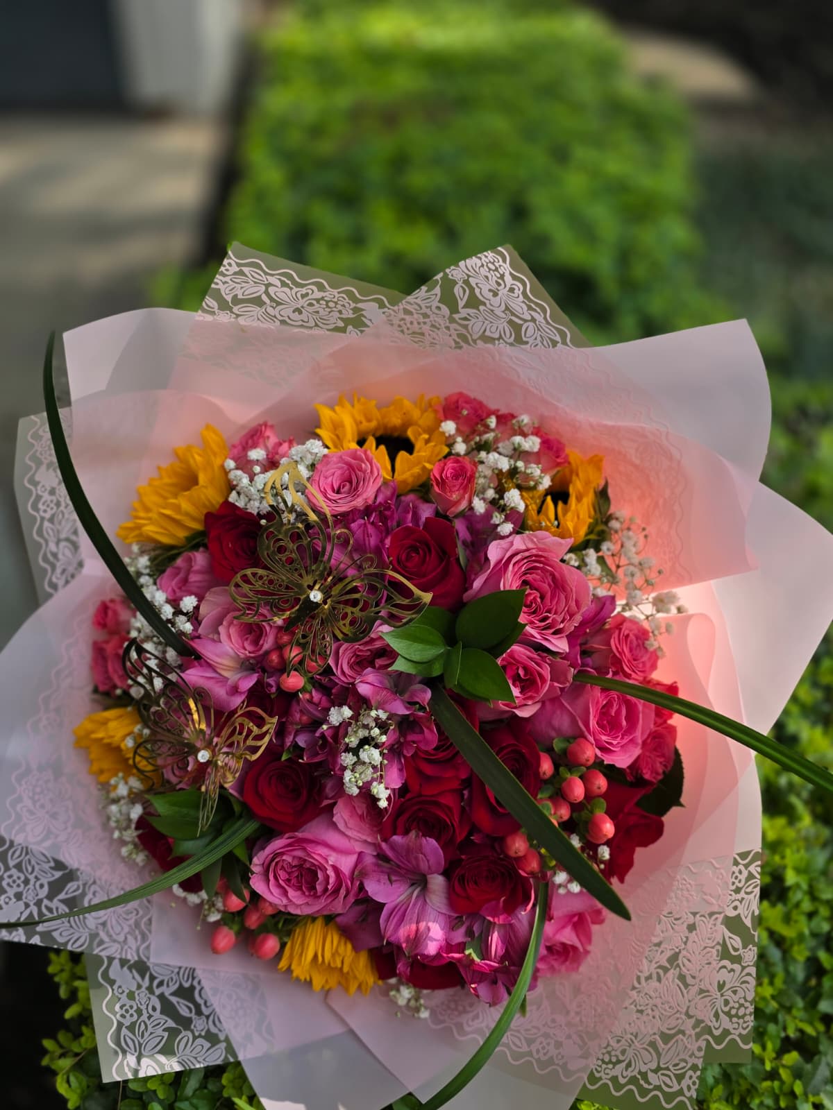 Bouquet of pink and red roses with yellow sunflowers in pink wrap