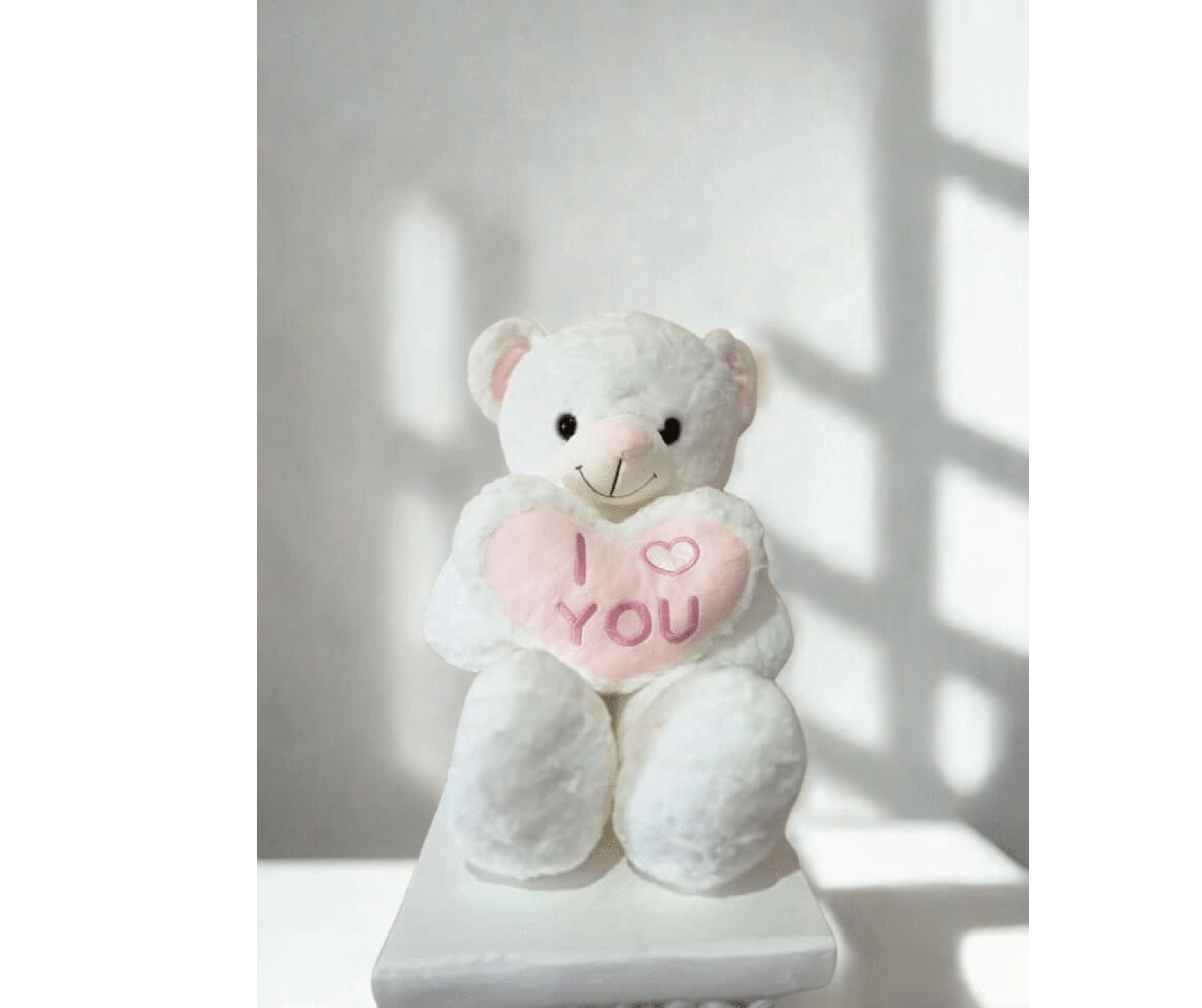 White teddy bear holding a pink heart that says I love you