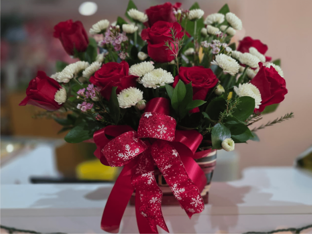 Bouquet of red roses and white button flowers with a red ribbon bow