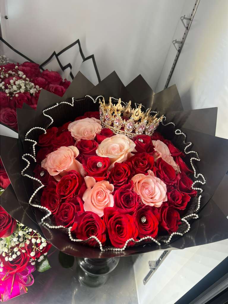 Bouquet of red and blush roses with a jeweled crown in black wrap