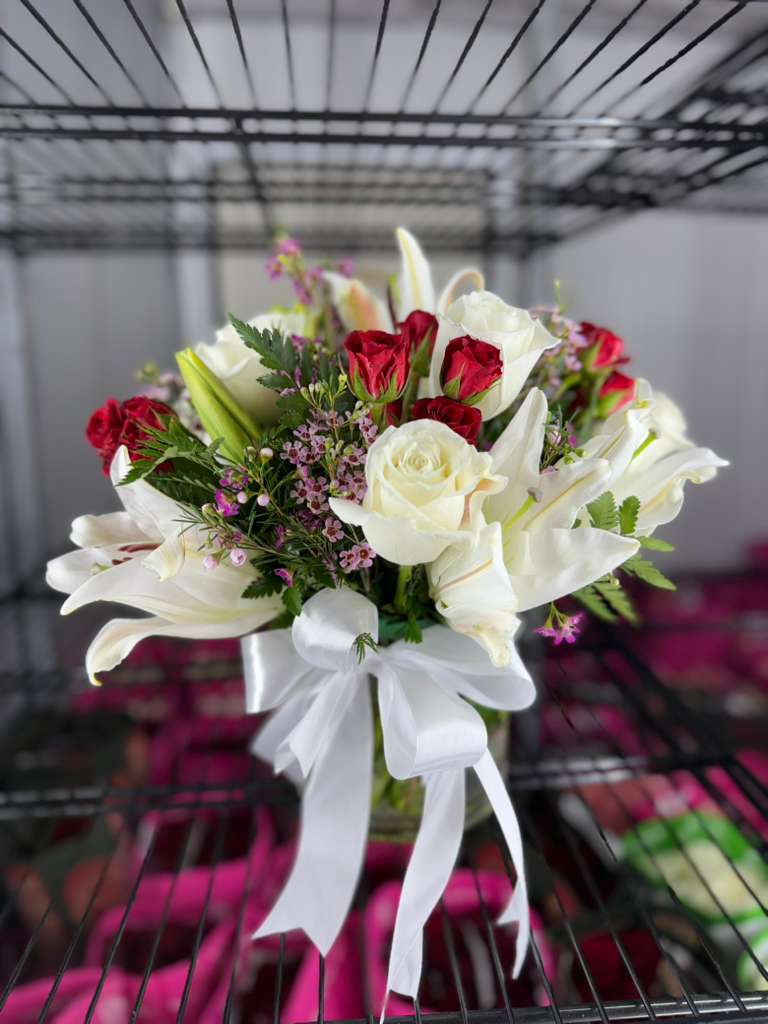 Bouquet of white lilies and red roses with a white ribbon