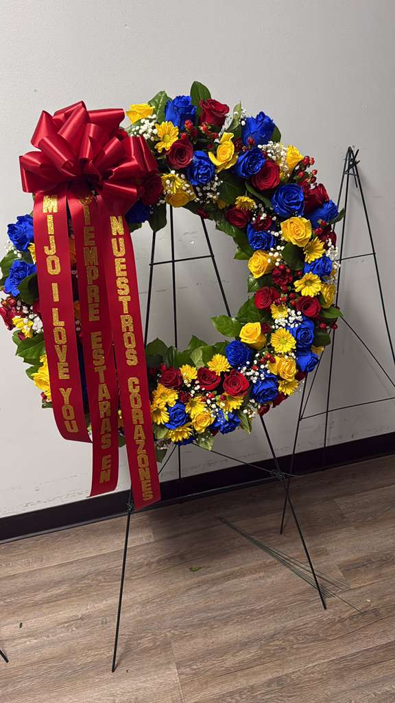 Large floral wreath with red, blue, and yellow flowers and a red ribbon