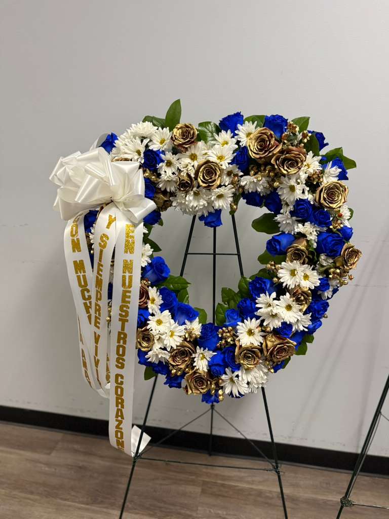 Heart-shaped floral wreath with blue, white, and gold flowers on a stand