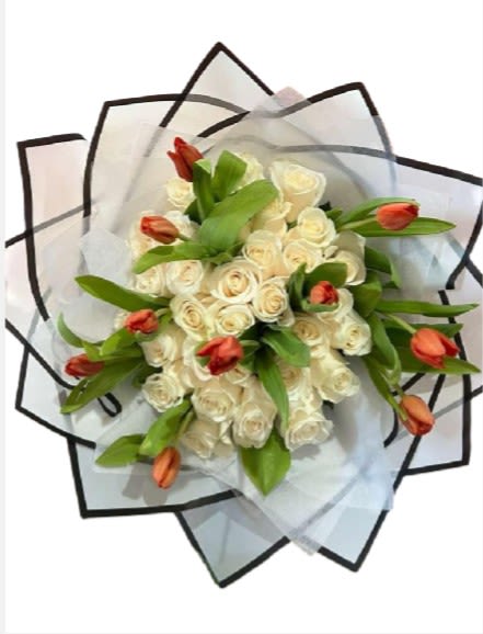 Bouquet of white roses with orange tulips wrapped in translucent paper