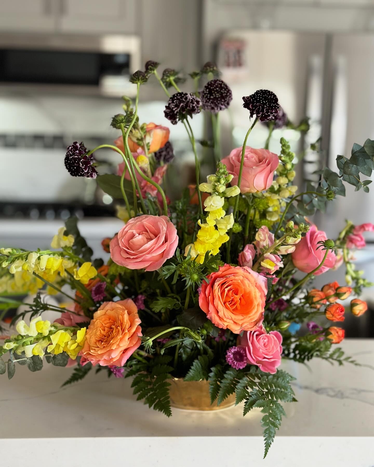 Romance in Bloom - A floral arrangement full of life, color, and natural movement, inspired by the freshness of spring. Springtime Charm features soft blush and coral roses combined with vibrant seasonal blooms and lush greenery, creating an elegant yet organic design. This arrangement is thoughtfully crafted to bring warmth, joy, and beauty to any space or special moment.  Each piece is handcrafted using fresh, seasonal flowers, maintaining the romantic and refined style that defines DM Blossom Boutique.