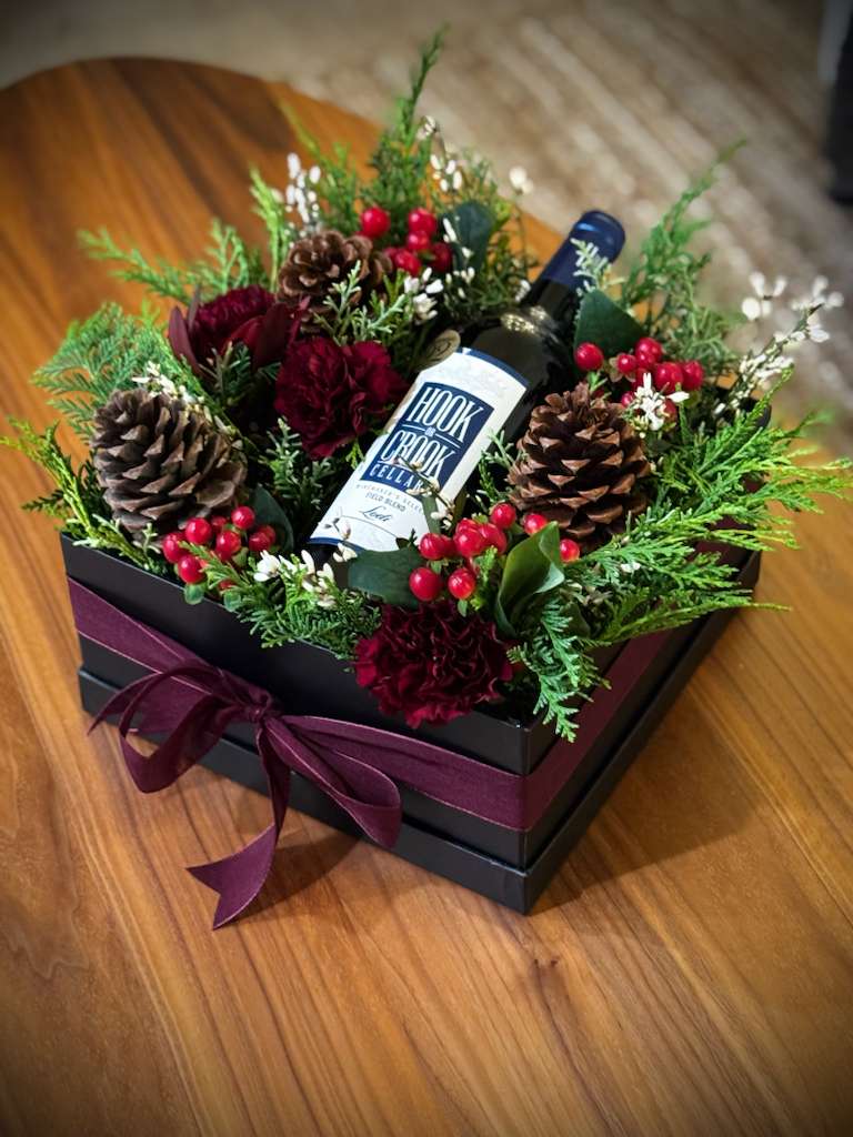 Holiday Wine Box Floral Arrangement – Limited Edition - Our Holiday Wine Box Floral Arrangement is a limited-edition design created to celebrate the season with elegance and warmth.  This arrangement features seasonal greenery, festive floral accents, natural textures, and refined details, all thoughtfully styled in a luxury box to beautifully complement a wine bottle.   Client provides their own wine bottle (standard 750 ml).  Perfect for holiday gifting, dinner parties, client appreciation, or special seasonal moments.  Each piece is handcrafted with care and offered in limited quantities to ensure quality and exclusivity.   Please contact us directly to check availability, color preferences, or to place your order.  Seasonal flowers may vary based on availability while maintaining the overall design and color palette. 