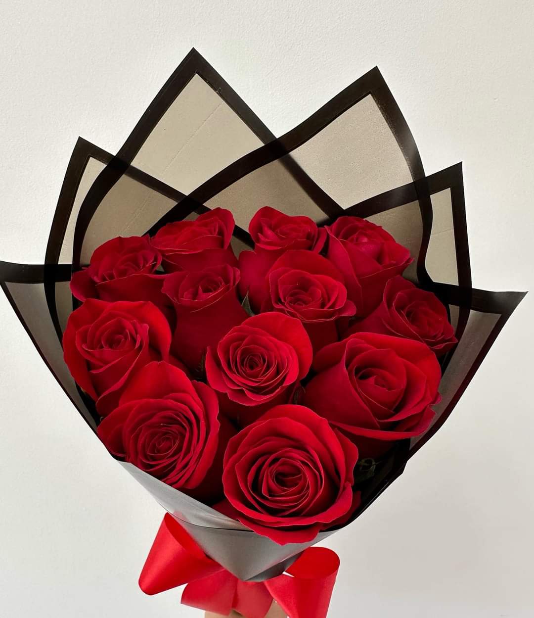 Bouquet of red roses wrapped in black and gray paper with a red ribbon