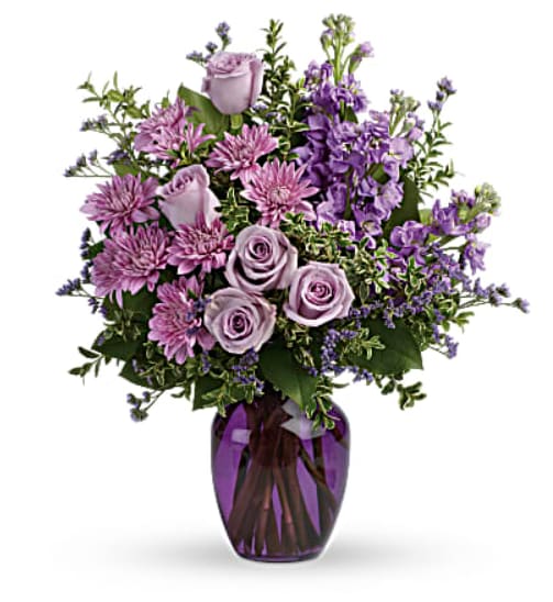 Lavender roses and purple flowers in a purple glass vase