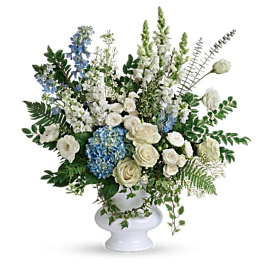 White and blue floral arrangement in a white pedestal vase