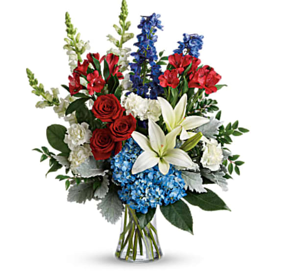 Bouquet of red roses, white lilies, blue flowers, and red blooms in a glass vase