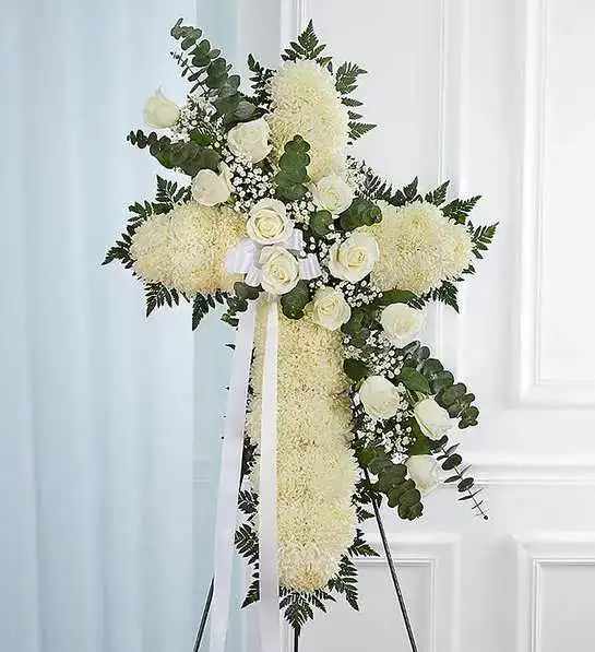 White Standing Cross - Honor a lifetime of faithful devotion with our beautiful standing cross arrangement. Our expert florists handcraft each of these impressive displays with a bed of white mums in the shape of a cross, and accent with a cascade of crisp white roses. It is a beautiful way to offer peace and comfort during a difficult time.