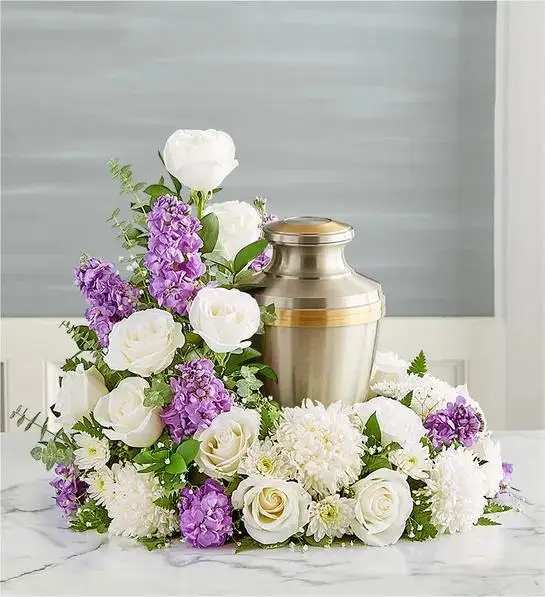 White and purple floral arrangement around a silver urn