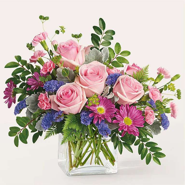 Pink roses and purple daisies in a clear glass vase