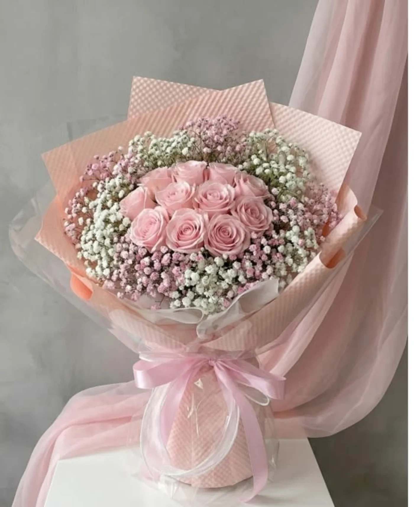 Pink rose bouquet wrapped in pastel paper with a ribbon