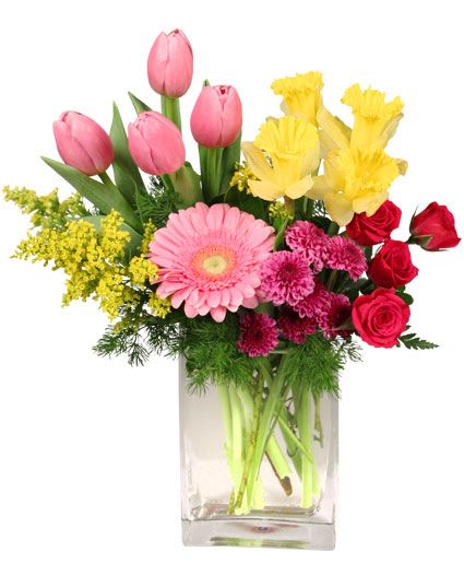 Mixed bouquet in a clear glass vase with pink tulips, yellow flowers, and red roses
