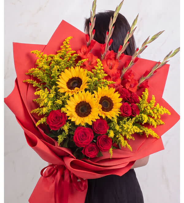 Bouquet of red roses and yellow sunflowers wrapped in red paper