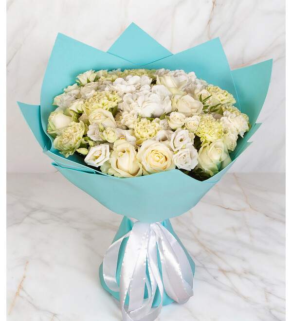 Bouquet of white roses and pale cream flowers wrapped in turquoise paper