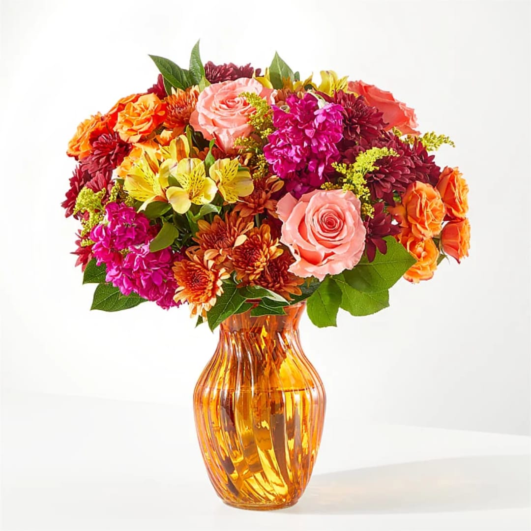Mixed bouquet of roses, chrysanthemums, and alstroemeria in an amber glass vase